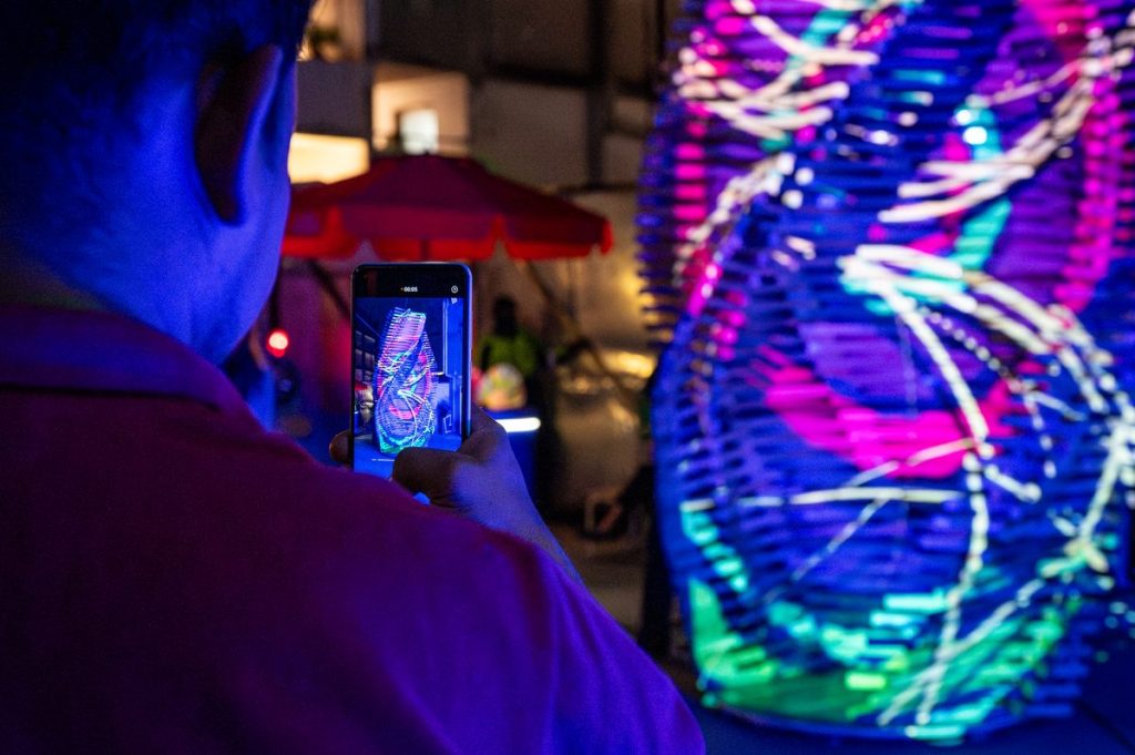 Persona fotografiando la escultura con mapping de colores vivos