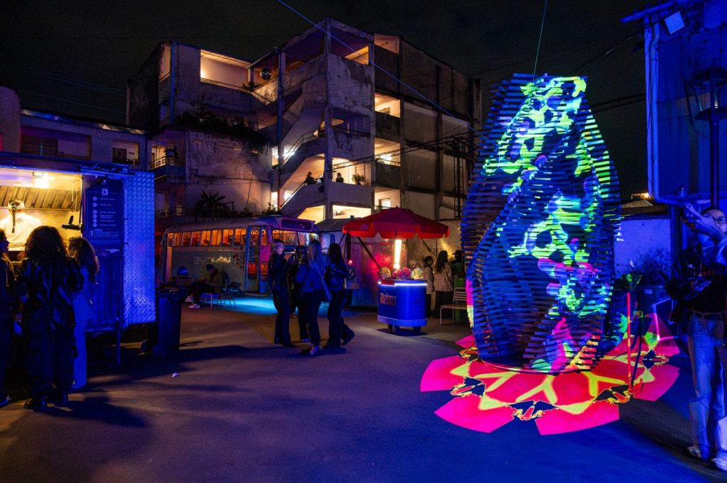 Torre de madera con proyección de mapping en verde y azul nocturno